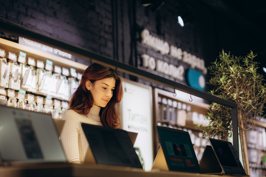 Femme devant différents ordinateurs dans un magasin de multimédia